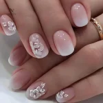 Faux ongles dégradé rose nude avec fleurs 3D blanches
